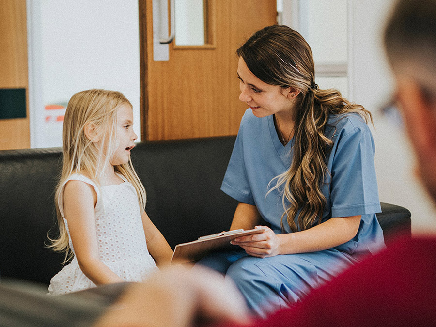 Young girl being interviewed by a female clinician in a waiting room.