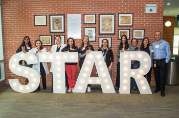 Group of STAR awardees gathered behind illuminated letters that spell out STAR. (Photo by Jacob Power Photography)