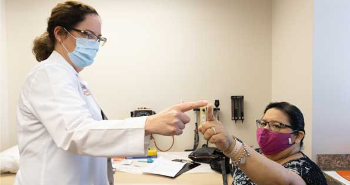 Photo of Louise McCullough, MD, PhD, reaching out her pointer finger to the pointer finger of patient Sophia Holton.