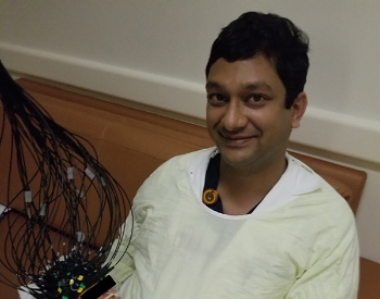 Photo of Manish N. Shah, MD, holding the patient while the Cap-based Transcranial Optical Tomography captures whole-brain imaging in minutes. (Photo credit: Manish N. Shah, MD)