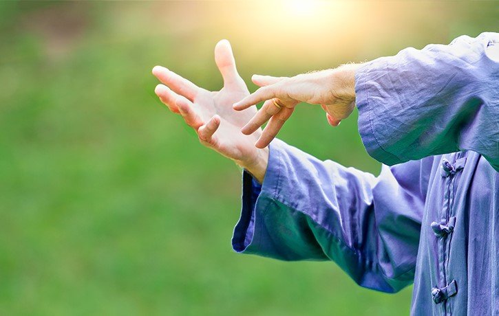 An instructor forms his hands during a tai chi exercise.
