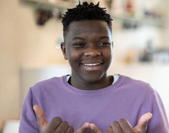 A teenage boy is shown signing in American Sign Language smiling. (Getty Images)
