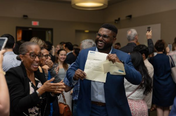 photo of Rosheem Browne at right celebrating Match Day while holding his letter. Photo by UTHealth Houston