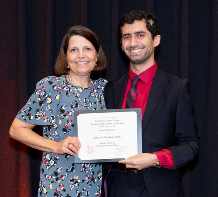 Dr. Bonita Wynkoop (left) accepts her John P. McGovern Outstanding Teaching Award during the 2022 DDS Senior Awards from Student Council President Ali Al Hatem.
