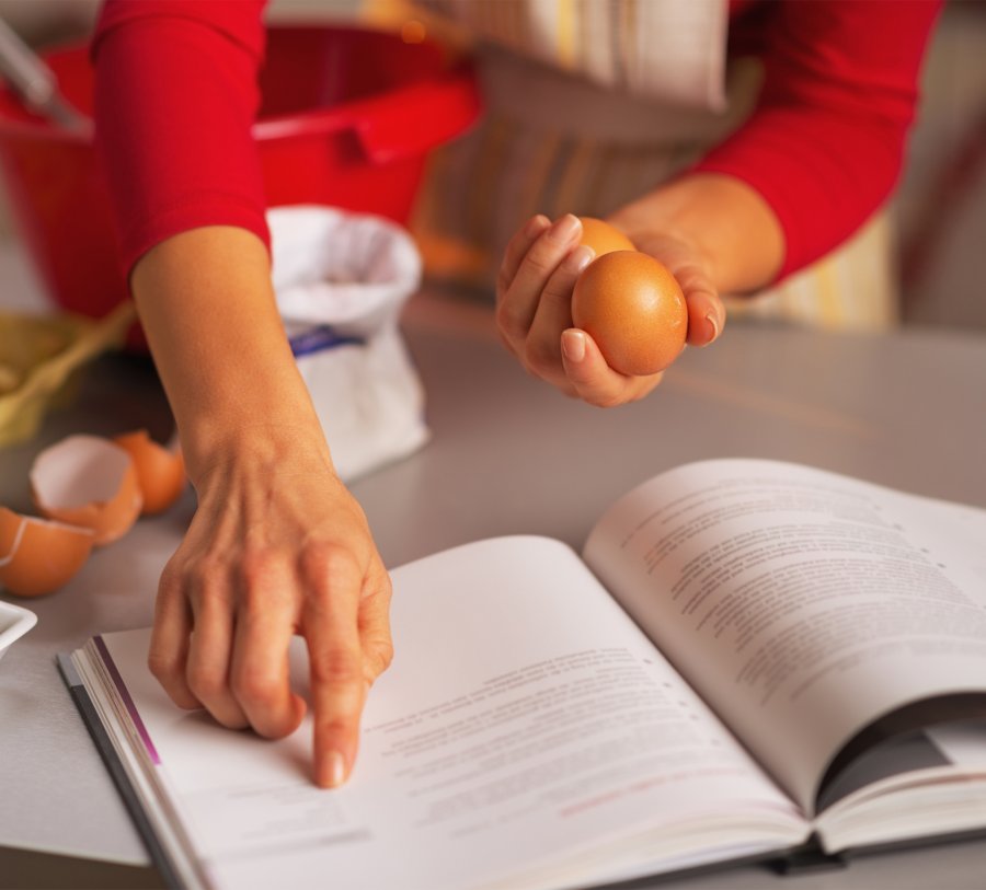Woman pointing at cookbook recipe.