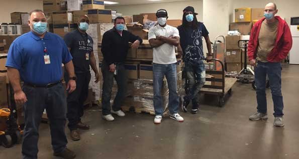Members of the Procurement Services team pose with boxes of PPE purchased from the global market.