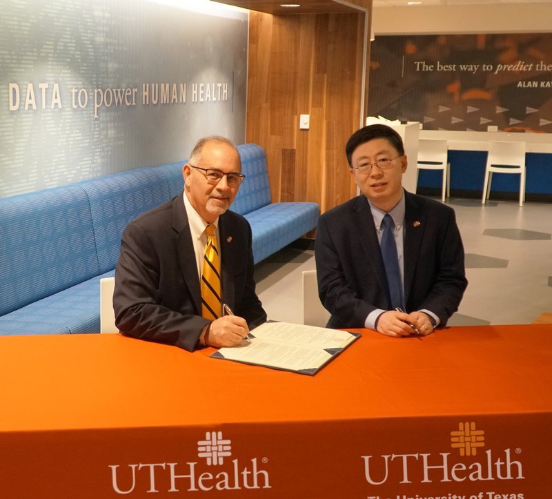 In this pre-pandemic photo, UTSD Dean John Valenza, DDS (left), and SBMI Dean Jiajie Zhang, PhD, complete formalities for a new program leading to a certificate in dental informatics. Photo by Queen Chambliss.