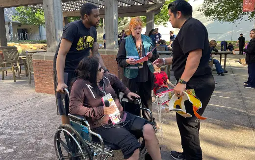Two students assist a person in need with a wheelchair at the 2024 Mass Casualty Simulation. (Photo by Angela Douglas, UTHealth Houston)