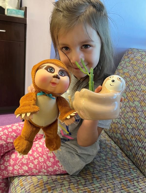 Kinsley holds the cactus plant in a sloth vase gifted to her by Wendy Chen, MD, after surgery, alongside the stuffed sloth toy she brought to clinic the same day. (Photo provided by Jenny Westbrook)