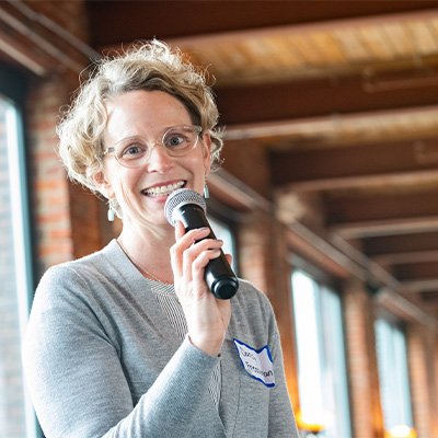 Photo of Darcy Freedman, PhD, MPH, holding a microphone and smiling. (Courtesy photo)