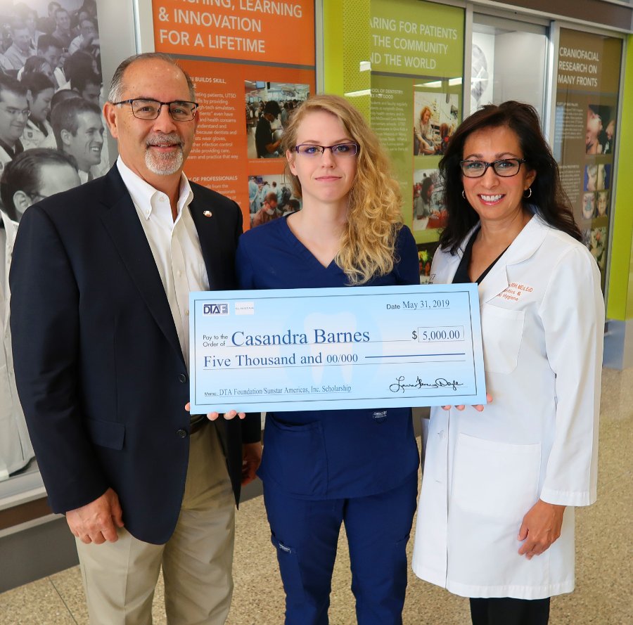 UTHealth dental student Casandra Barnes (center) holds an oversize check signifying her $5,000 scholarship. Also pictured: Dean John Valenza, DDS, and Community Outreach Director Margo Melchor, RDH, EdD.