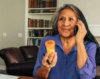Stock image of an older adult on the phone and holding a prescription bottle. (Photo by Getty Images)