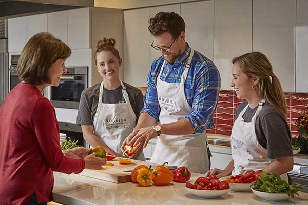Photo of Wesley McWhorter, MS, RD, preparing food with Laura Moore, MEd, RD, and students watching (Photo by Terry Vine)