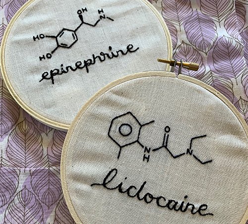 Two embroidery hoops showing the chemical structure for epinephrine and lidocaine in black thread on white background