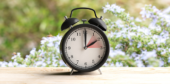 Photo of clock in front of flowers.
