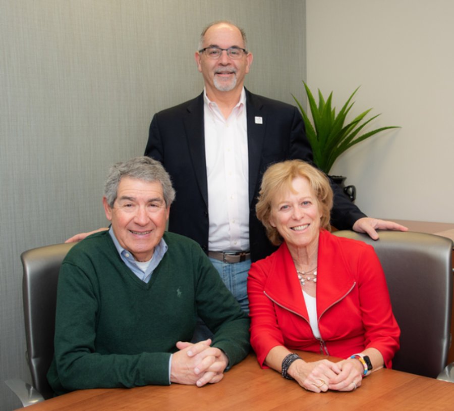 Husband and wife, Wayne Dorris, PhD (left), and Jacqueline T. Hecht, PhD (right) post with Dean John A. Valenza, DDS.
