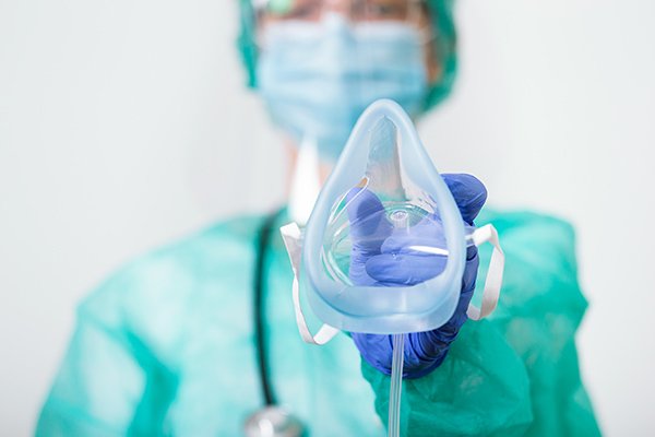 Photo of a hospital worker holding an oxygen mask. (Photo credit: Getty Images)