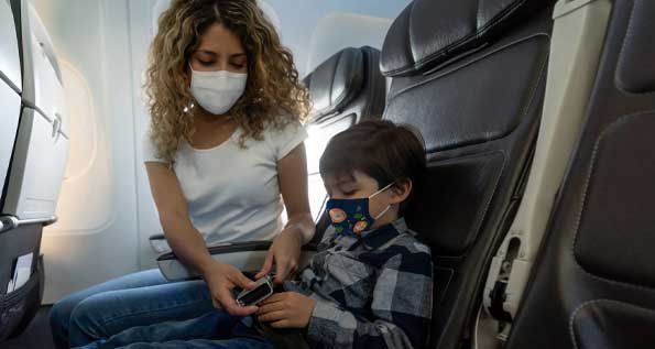 Image of a woman buckling the seat belt of a little boy on an airplane. (Photo by Getty Images)