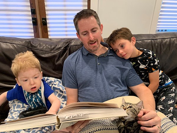 Nathan Hoot, MD, PhD, reads to his two sons on the couch.