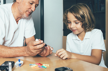 Image of father showing child how to check his blood sugar (Photo by: Getty Images)