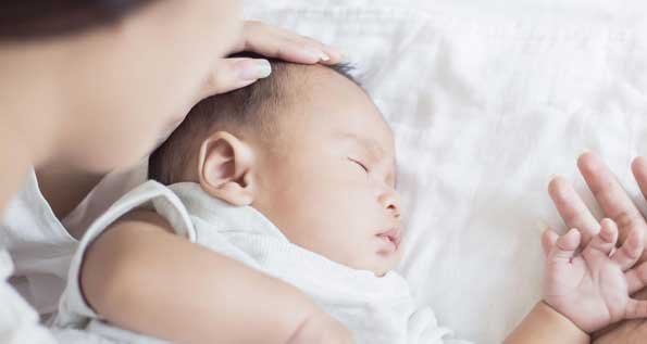 Image of a woman cuddling a sleeping infant.