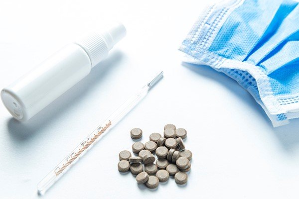 Photo of pills, a thermometer, and a surgical mask. (Photo credit: Getty Images)