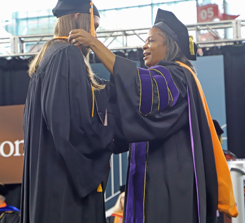 Dr. Hildreth Eloi presents a nursing pin to a BSN graduate at the 2022 spring commencement ceremony. (Photo courtesy Sherri Green, Cizik School of Nursing)