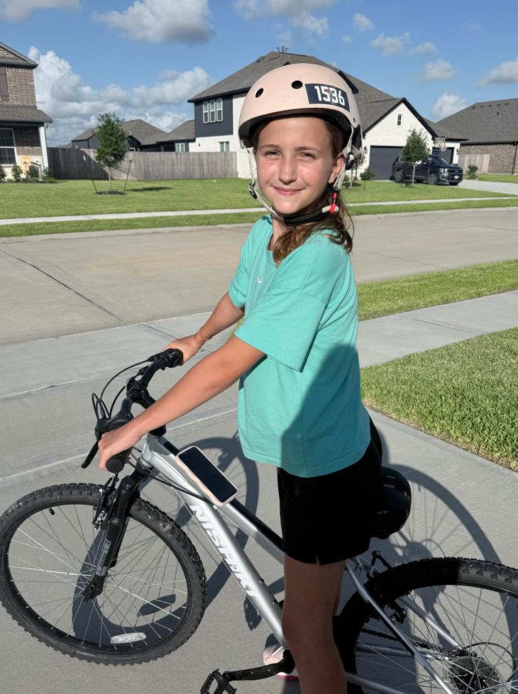 Halle Neely, 11, pictured riding her bike with a helmet after a scooter injury left her with an epidural hematoma that required brain surgery. (Photo by Heather Neely)