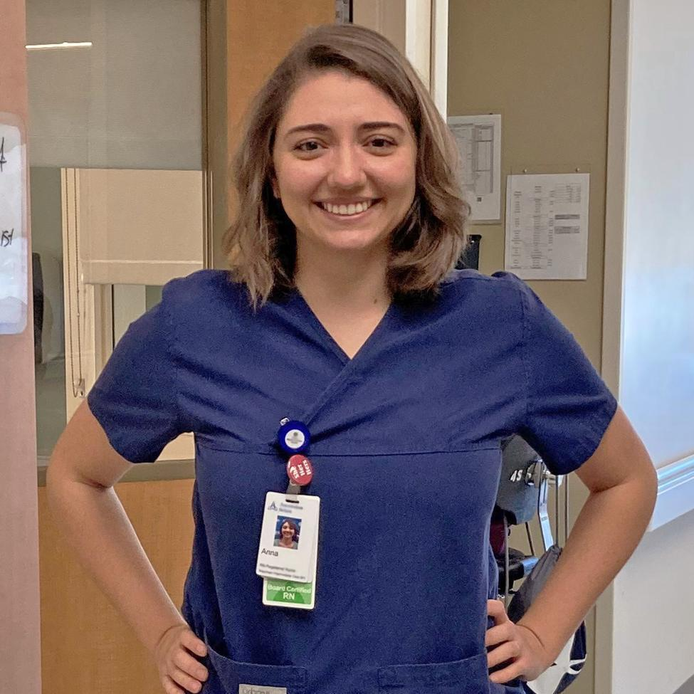 Photo of Annie Steinhauser, MSN, RN, PCCN, standing with her hands on her hips and smiling in a clinical setting.
