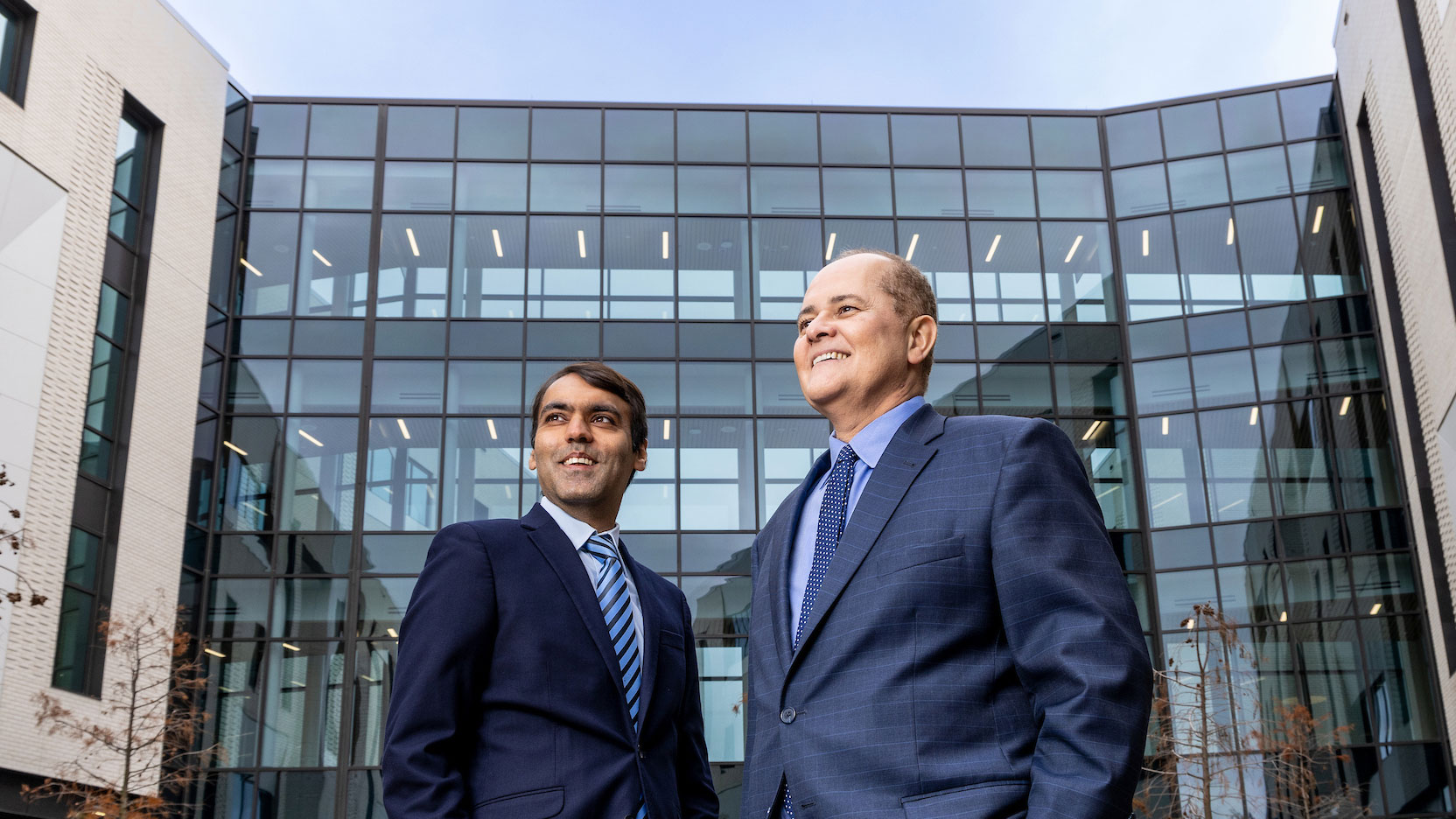 Forced perspective upward angle photo of Lokesh Shahani, MD, MPH, FACP and Jair Soares, MD, PhD with the John S. Dunn Behavioral Sciences Center in the background