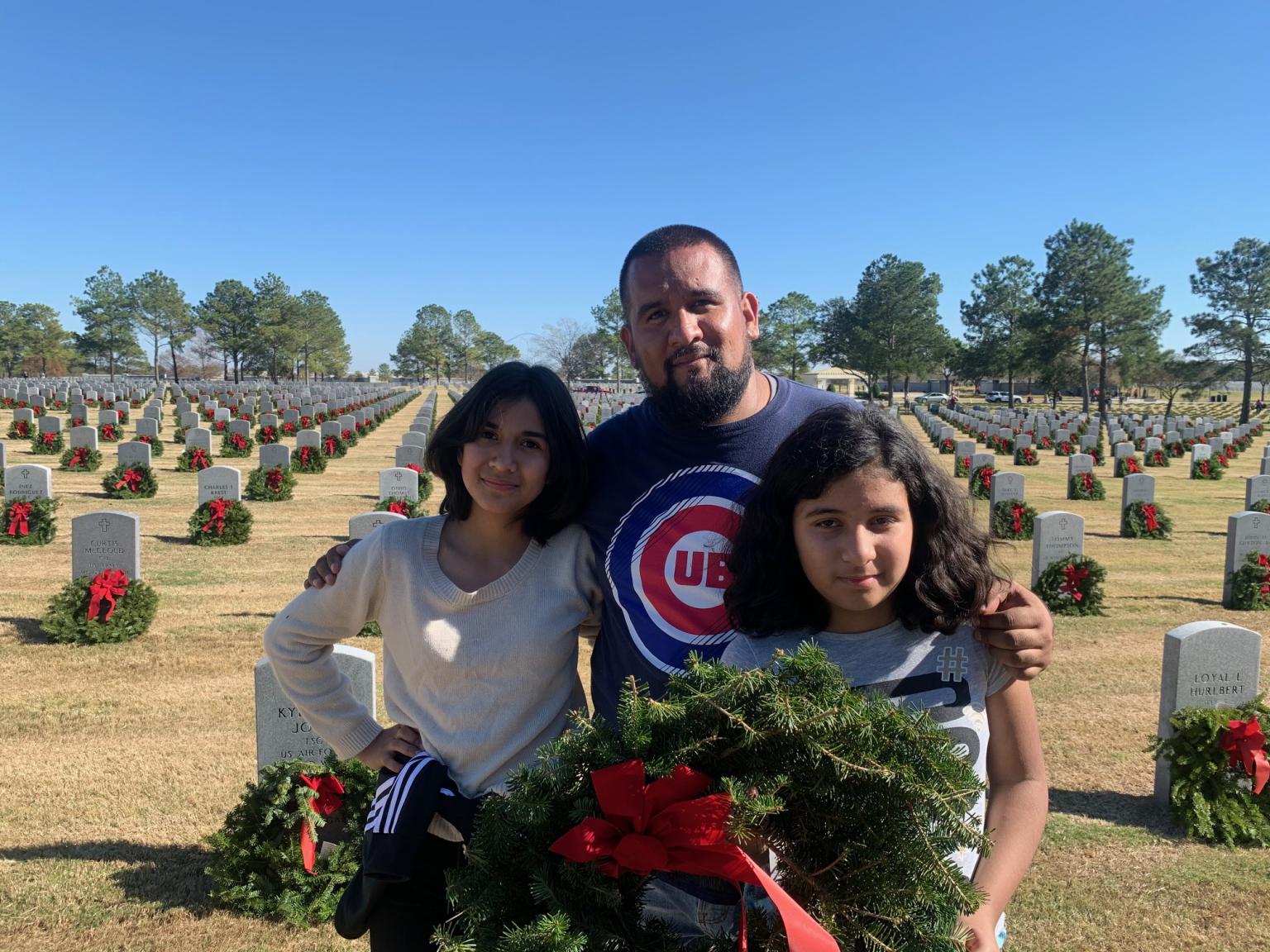 family placing wreaths at graveyard