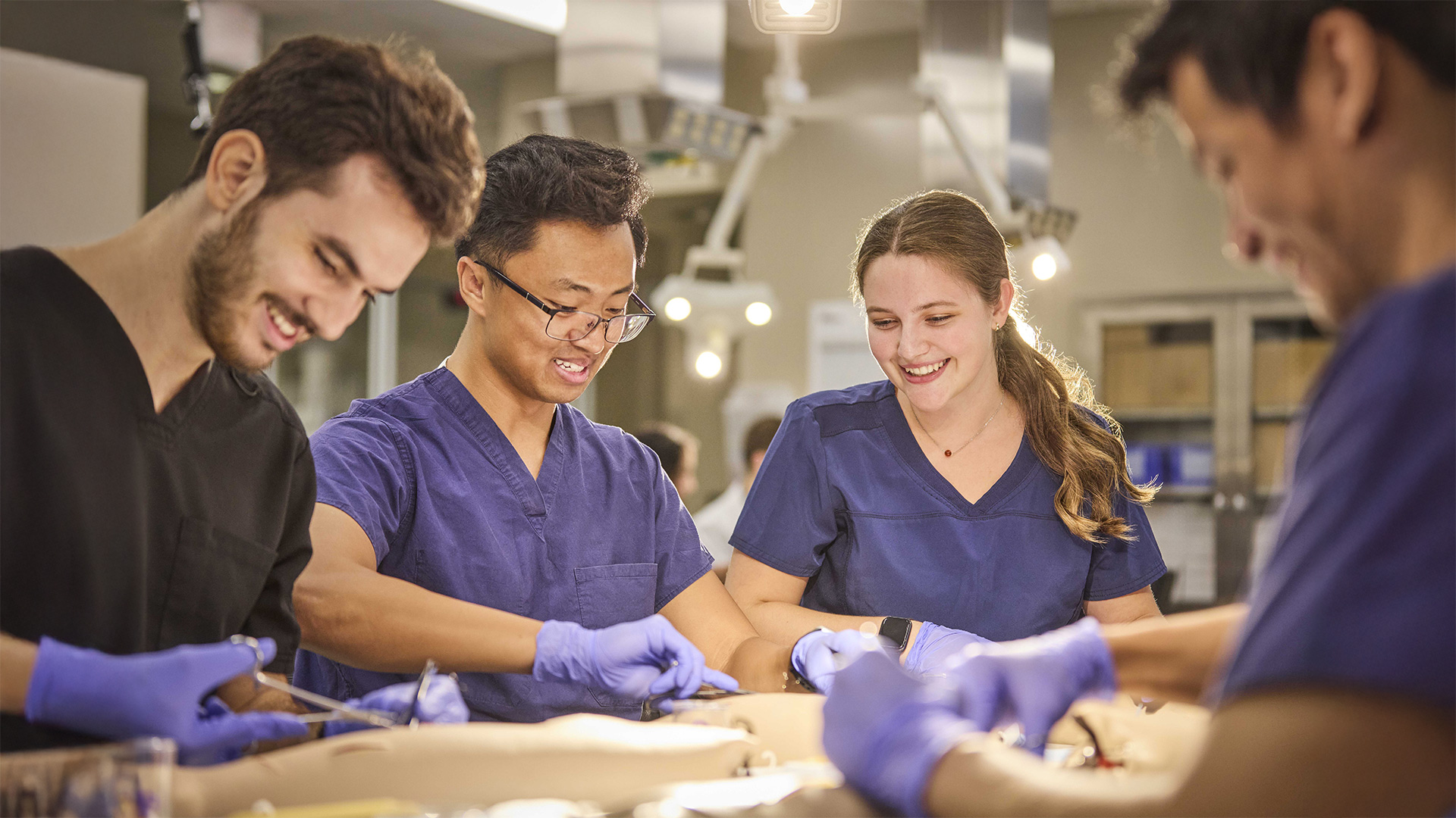 Four students surrounding an operating table practicing hands on surgical work