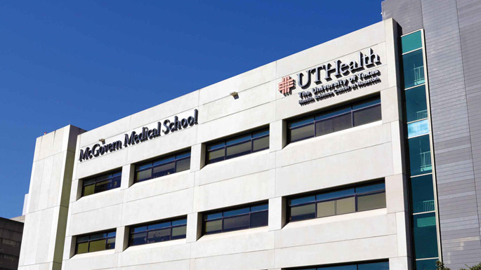 Exterior view of the McGovern Medical School building at UTHealth Houston, with institutional signage displayed on a modern cream-colored facade.
