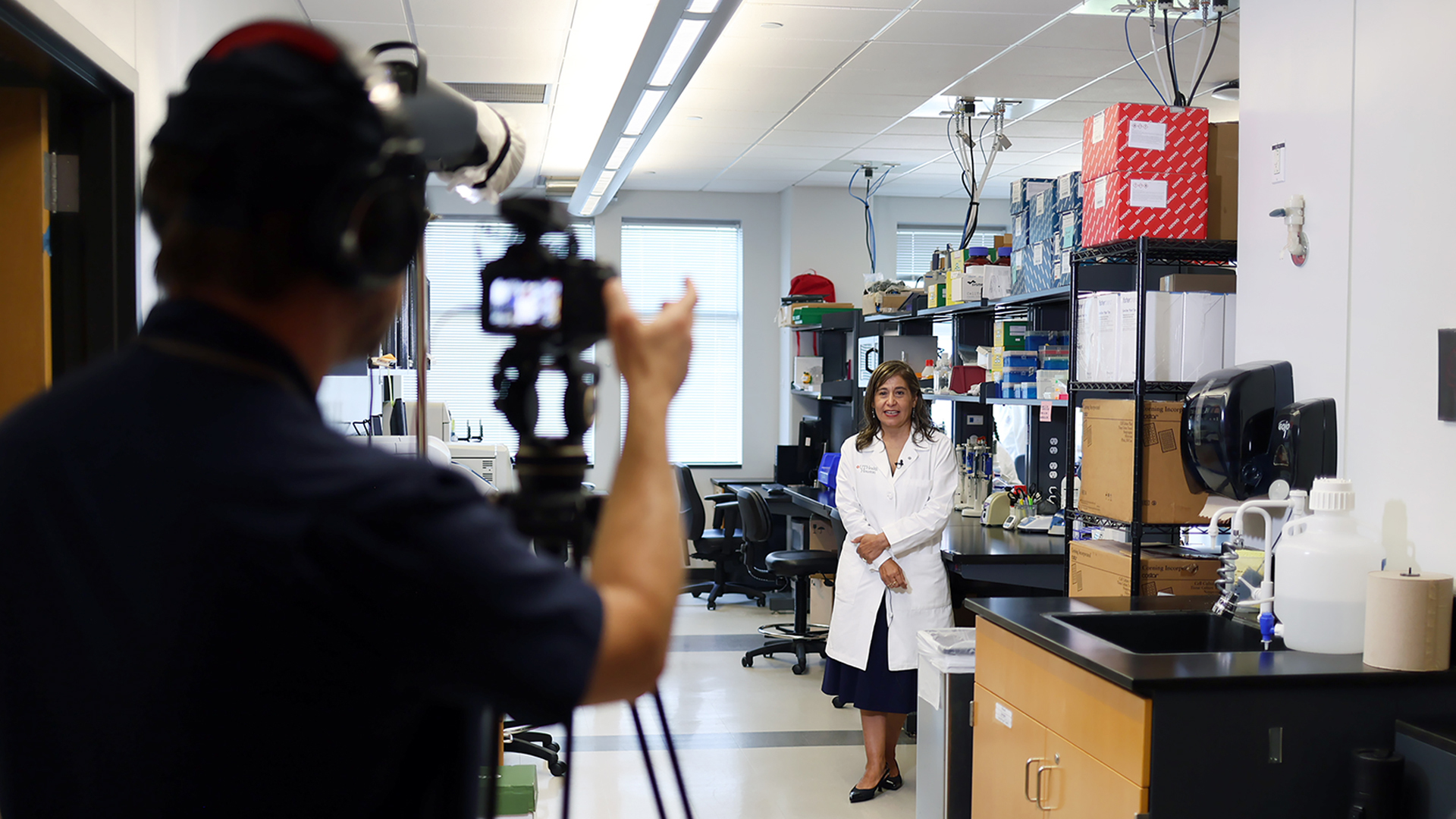 A view of a member of the Marketing and Communications team recording a video of a faculty member in their lab
