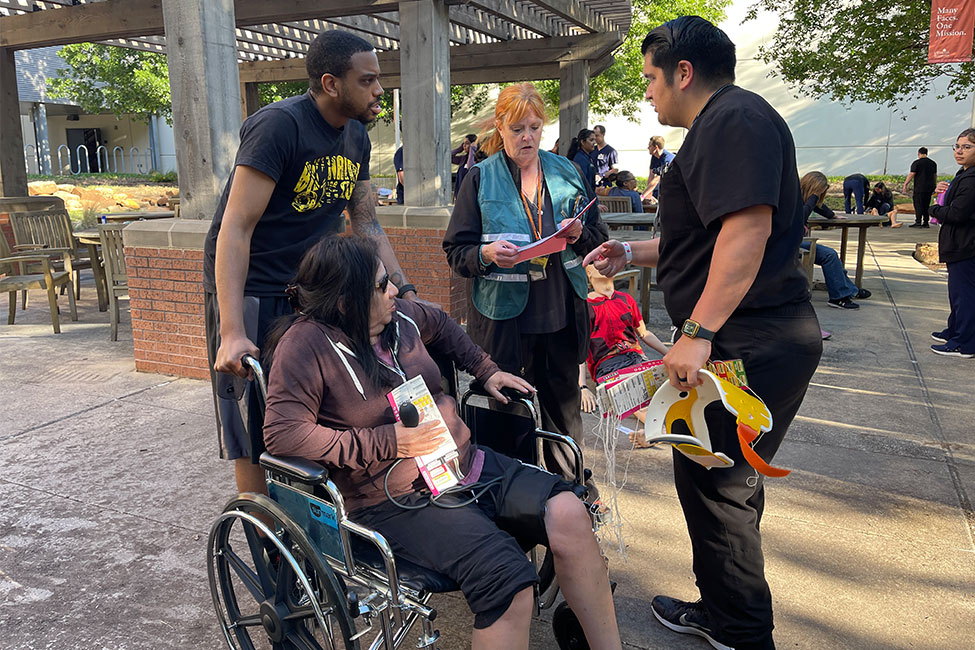 Two students assist a person in need with a wheelchair at the 2024 Mass Casualty Simulation. (Photo by Angela Douglas, UTHealth Houston)