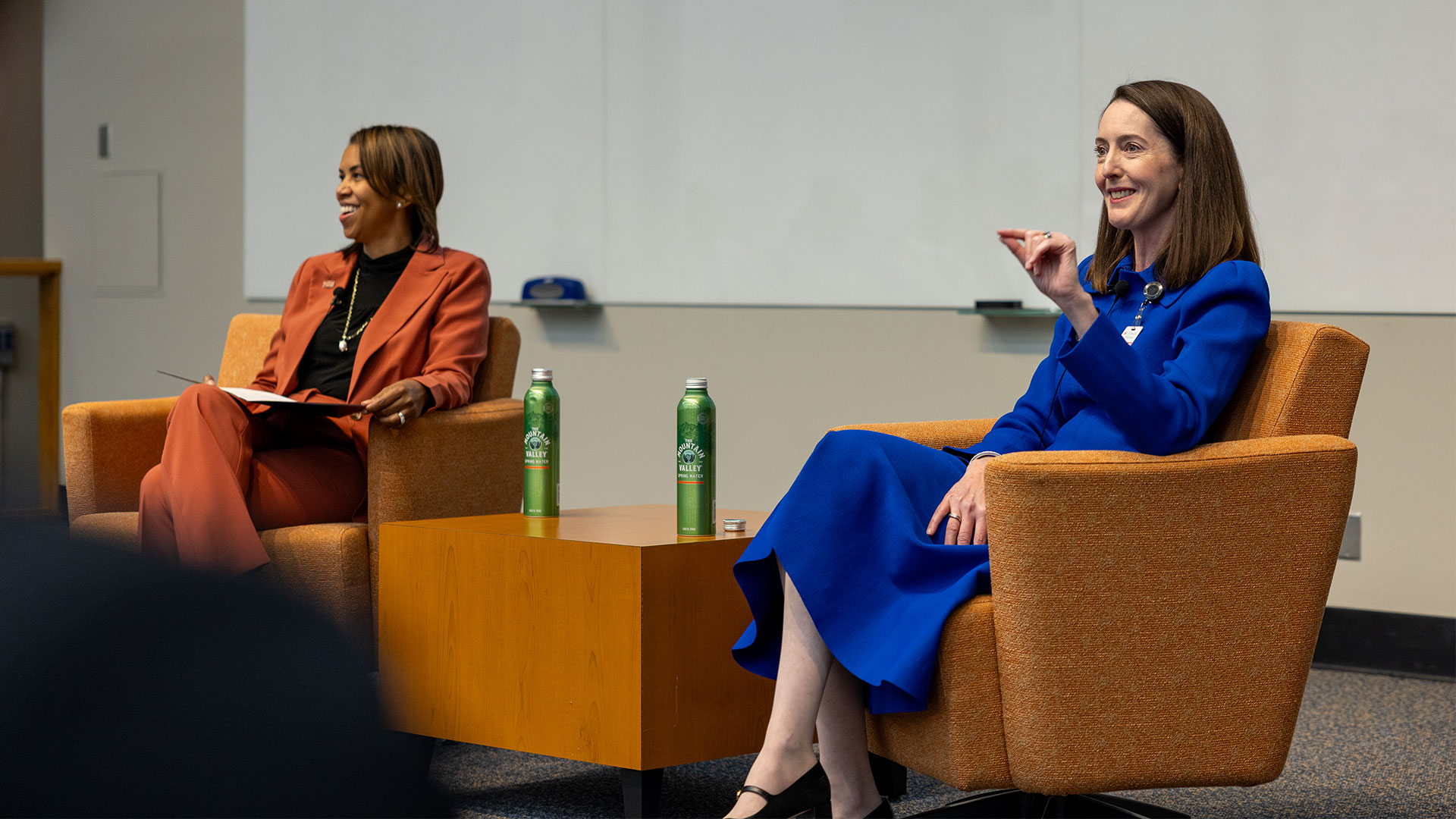 President Kibbe and Dr. Love sitting in orange chairs and speaking to an audience.