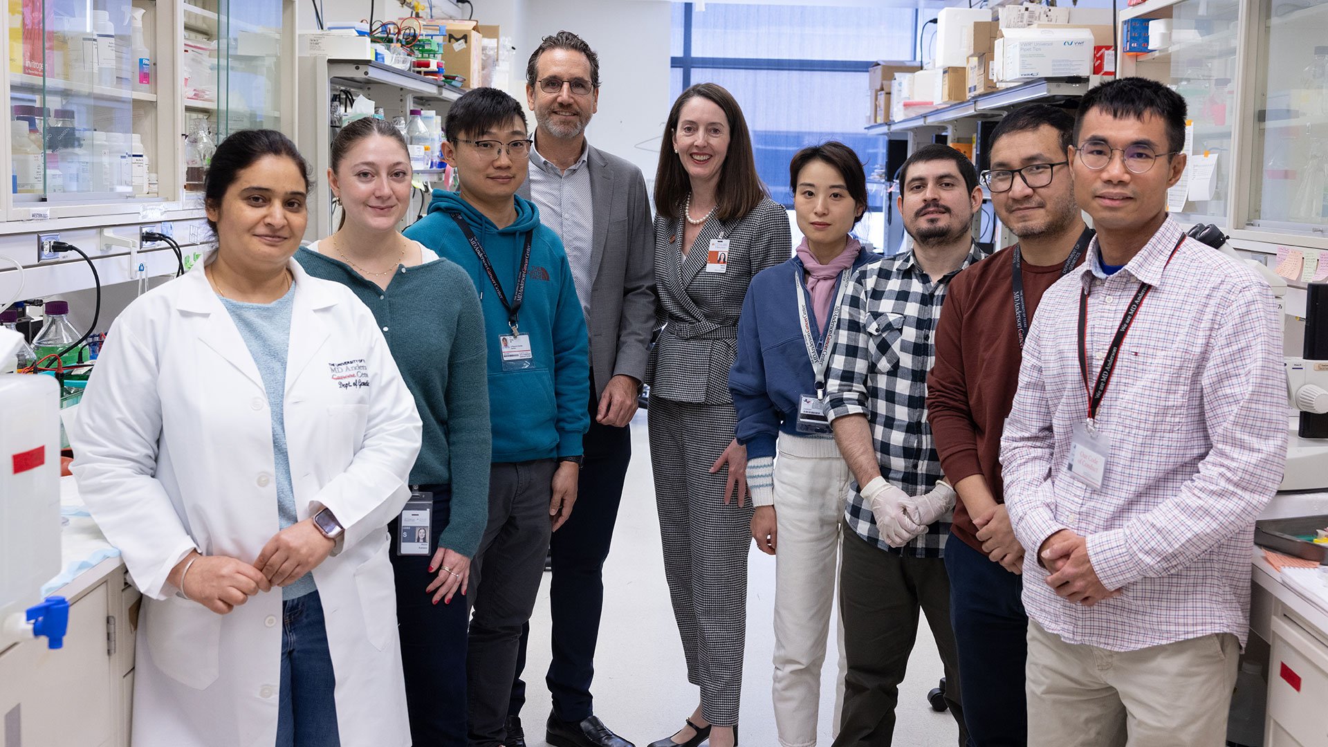 Nine total people standing a lab posing for a photo.