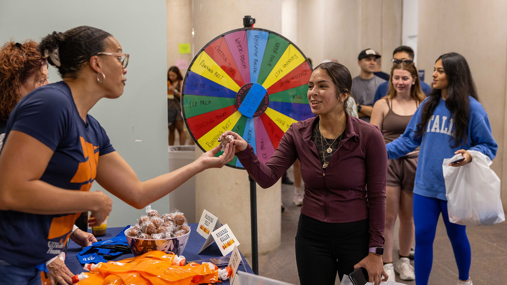 Health fair attendee receives an item at an interactive UTHealth Houston booth featuring a prize wheel.