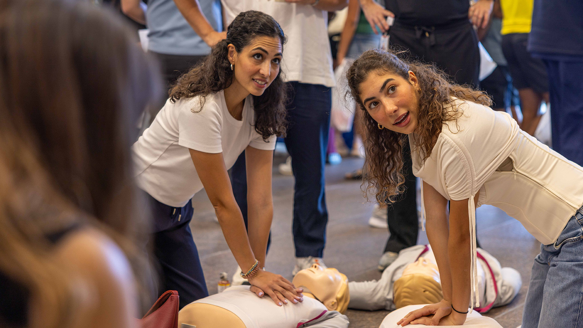 Two participants practice chest compressions on CPR training manikins during a UTHealth Houston health fair.