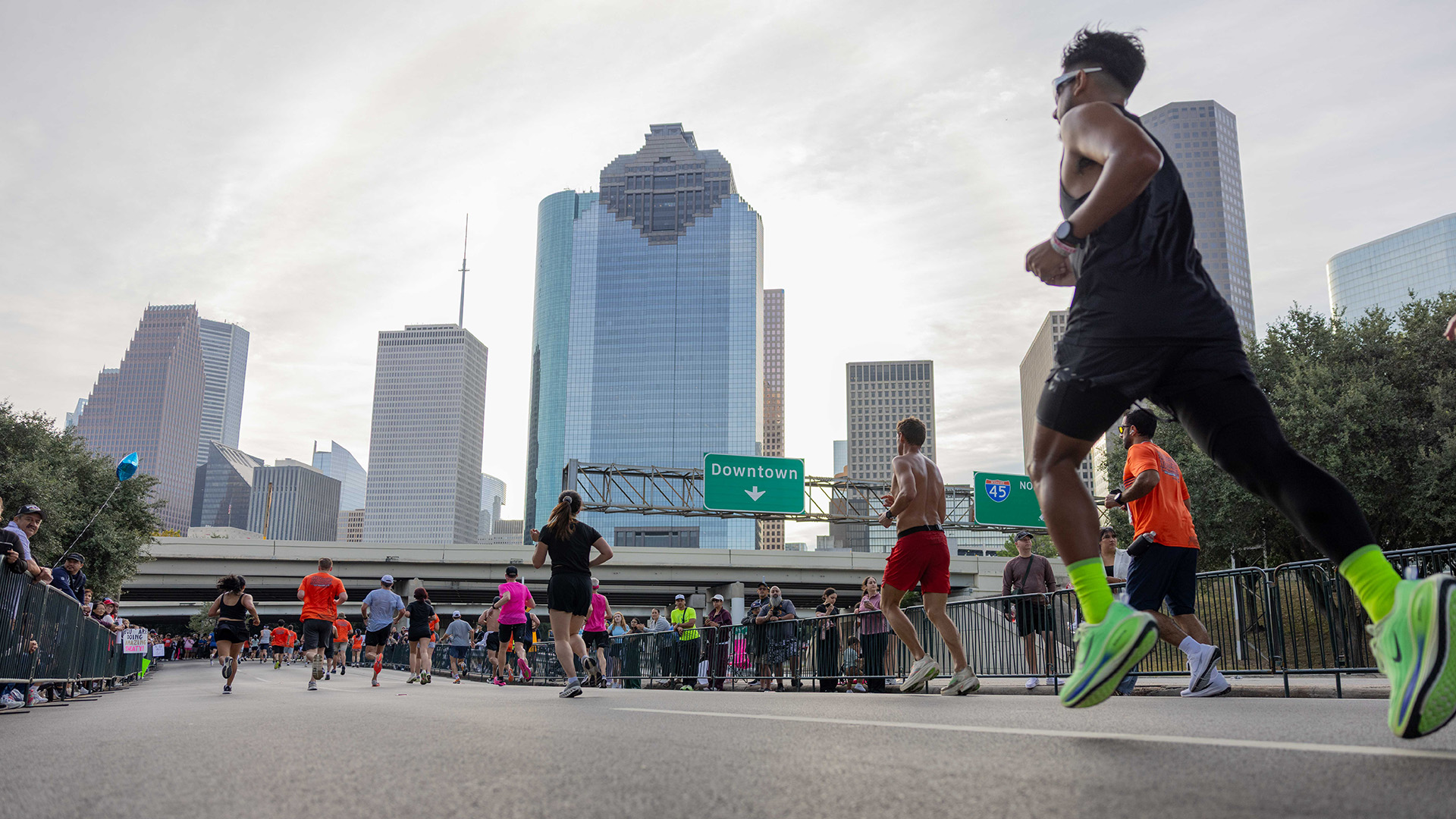 Runners make their way toward downtown Houston with the city skyline rising above the race course.