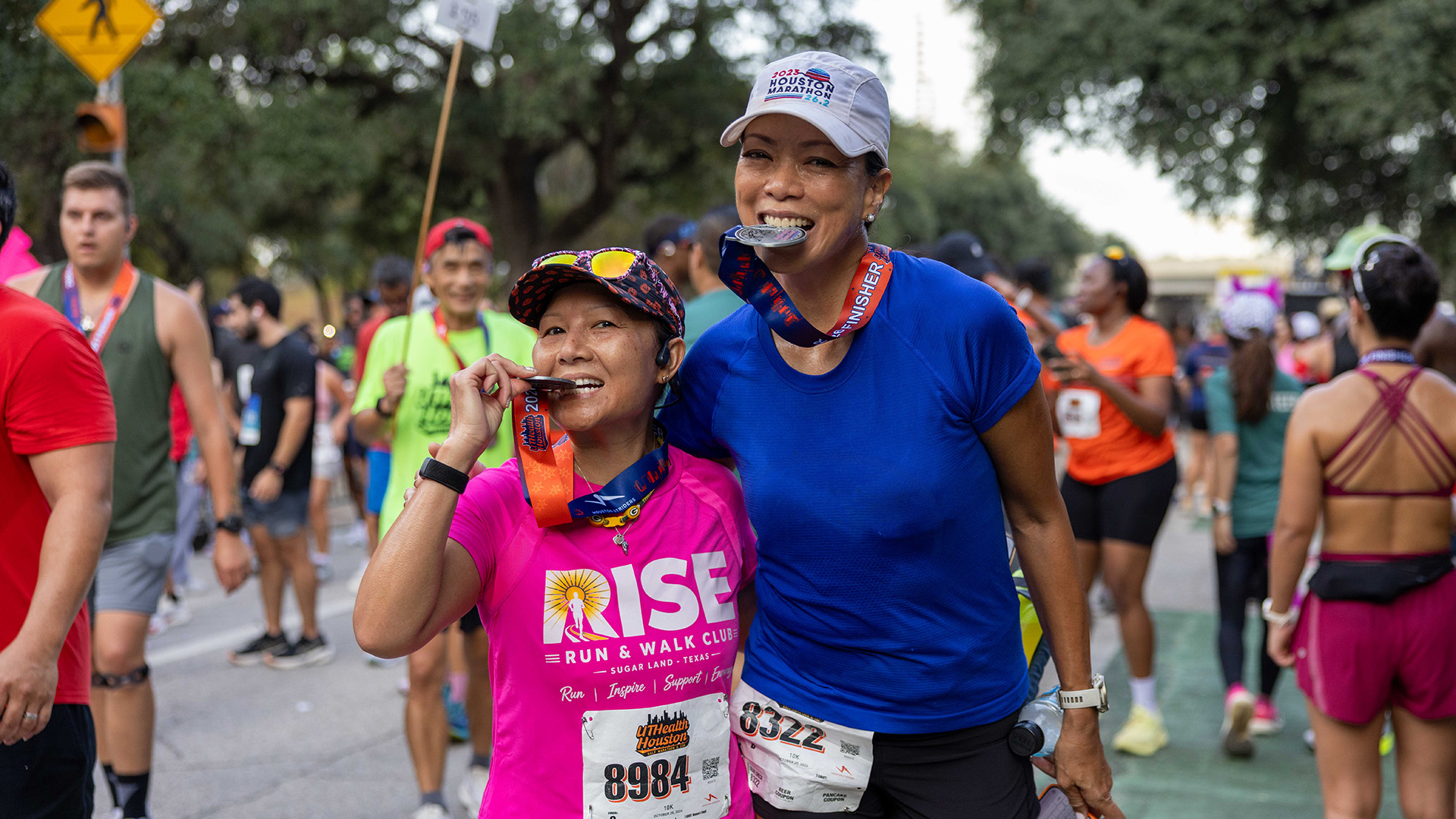Two smiling runners pose together with their finisher medals after completing the Houston Half Marathon.