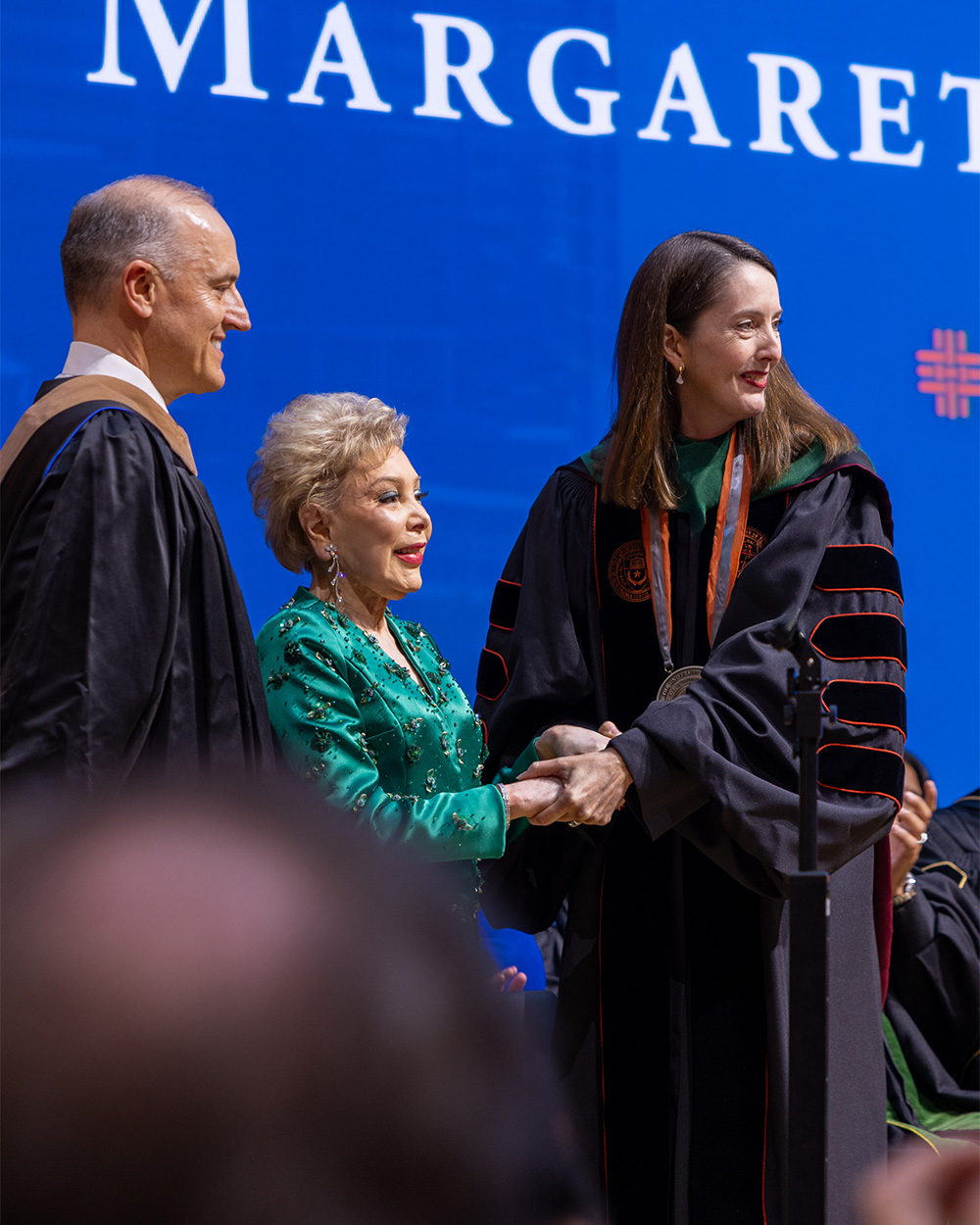 President Melina Kibbe shakes hands with a guest on stage during her investiture as president of UTHealth Houston.