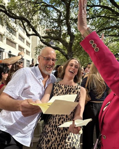 Katie Abel smiling and holding her Match Day envelope while celebrating with others in a crowd outdoors.