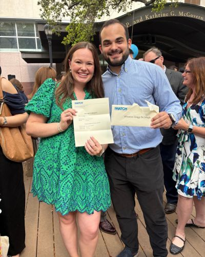 Graham Brem and Winston Zingg standing side by side, smiling and holding their Match Day envelopes during an outdoor celebration.