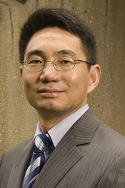 Zhongming Zhao in suit standing posing near the building in the background.